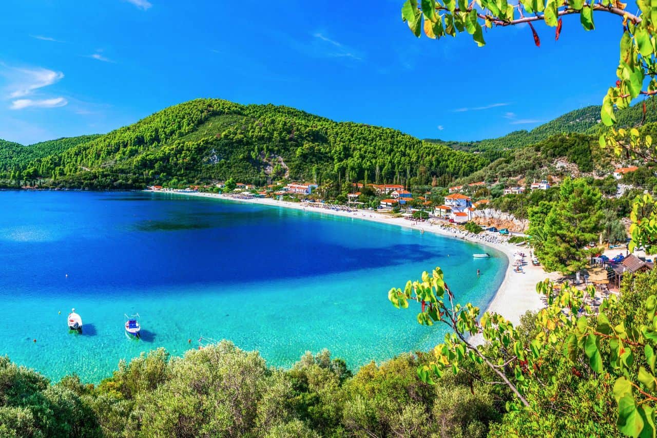 a beautiful turquoise beach underneath rolling forested hills